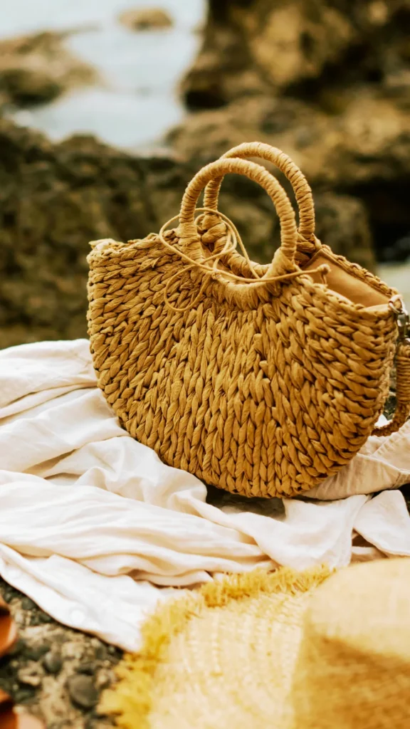Structured woven straw tote bag resting on a white linen shirt, a perfect chic summer outfit accessory for warm weather.